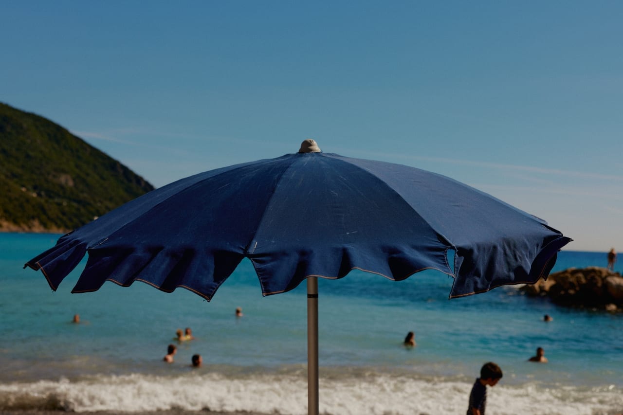 Sombrilla azul en una playa con bañistas