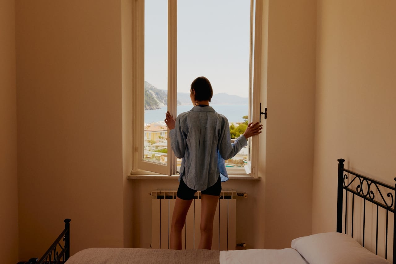 Huésped abriendo la ventana de su habitación hacia el mar